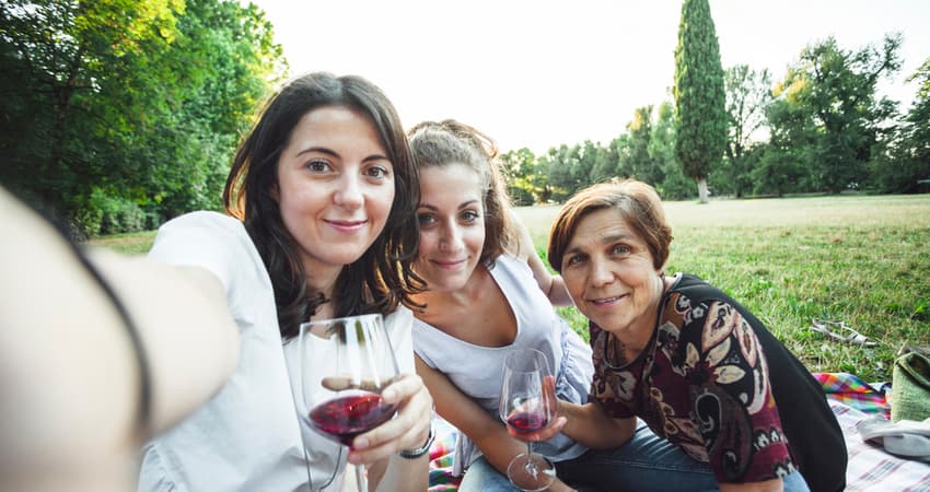 two young women and their mother having wine outside