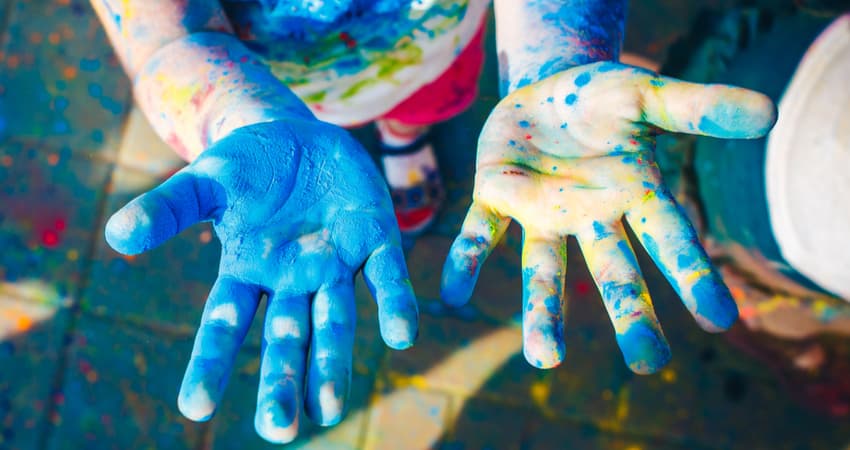 a child's hands covered in paint at a festival