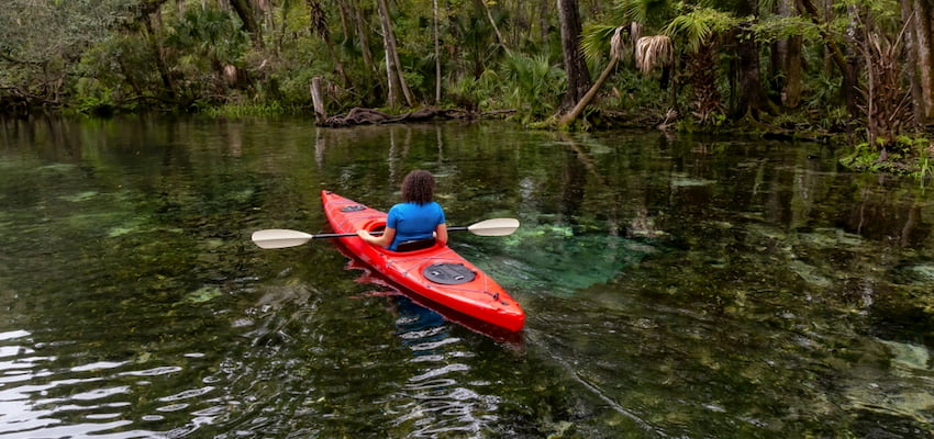 a woman kayaks on clear spring waters at Wekiwa Springs near Orlando Florida