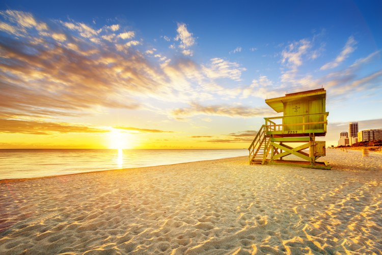 Sunset over a beach in Miami with a lifeguard stand visible 