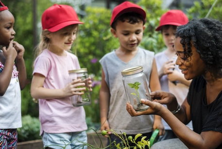 Children holding specimens in jars outdoors