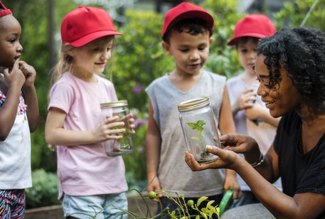 Children holding specimens in jars outdoors