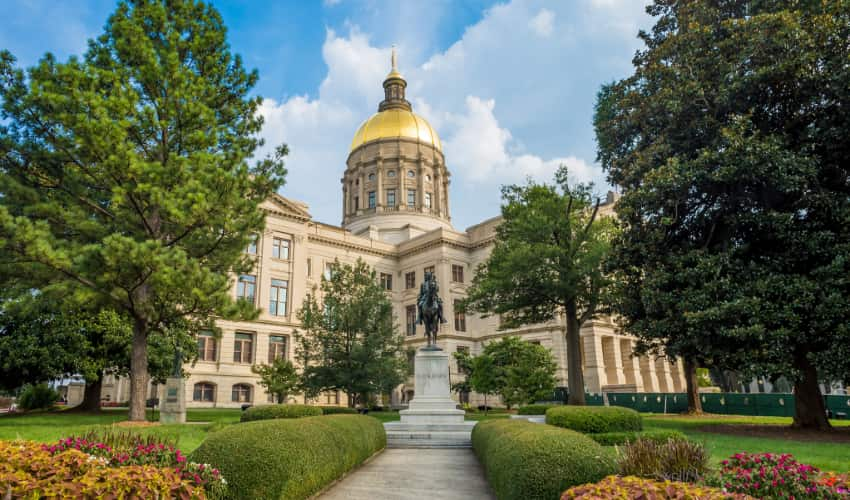 the Georgia State Capitol Building amidst trees and a statue