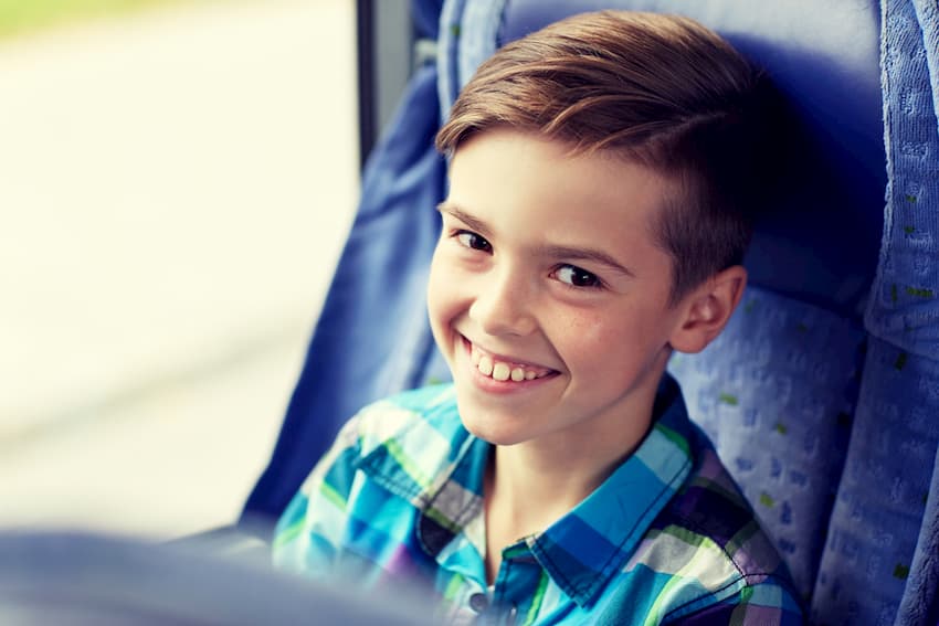 child smiling seated on a charter bus