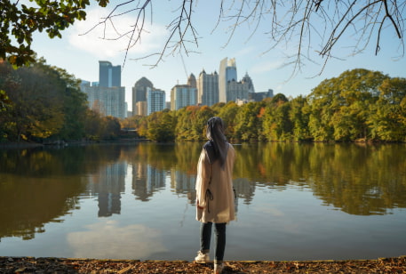 a woman in a headscarf admires the Atlanta skyline from Piedmont Park