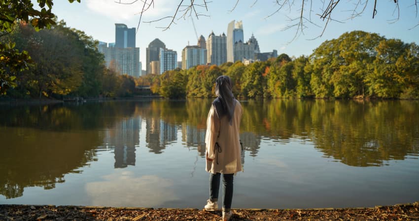 a woman in a headscarf admires the Atlanta skyline from Piedmont Park