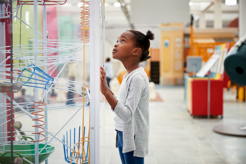 Little girl at a science museum exhibit looking at it in wonder