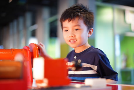 a child interacts with a gear puzzle in a children's museum