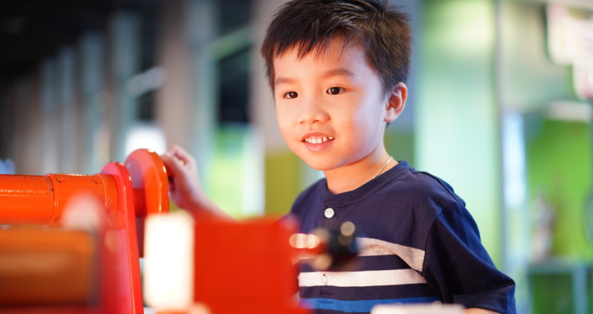 a child interacts with a gear puzzle in a children's museum