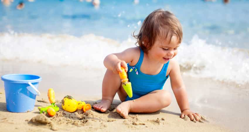 A young child playing with sand at the beach