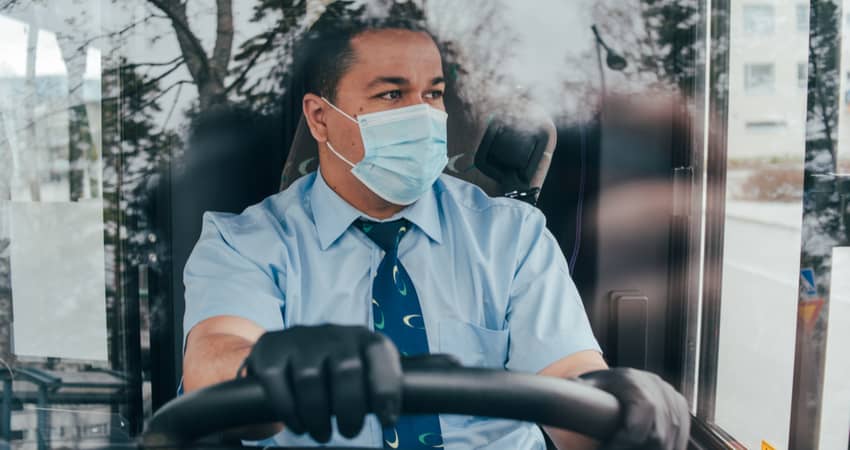 A charter bus driver wearing a mask while behind the wheel.