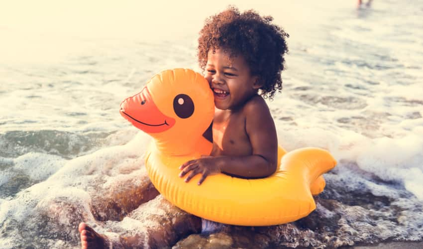 A young child in a floaty playing at the beach