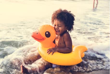 A young child in a floaty playing at the beach