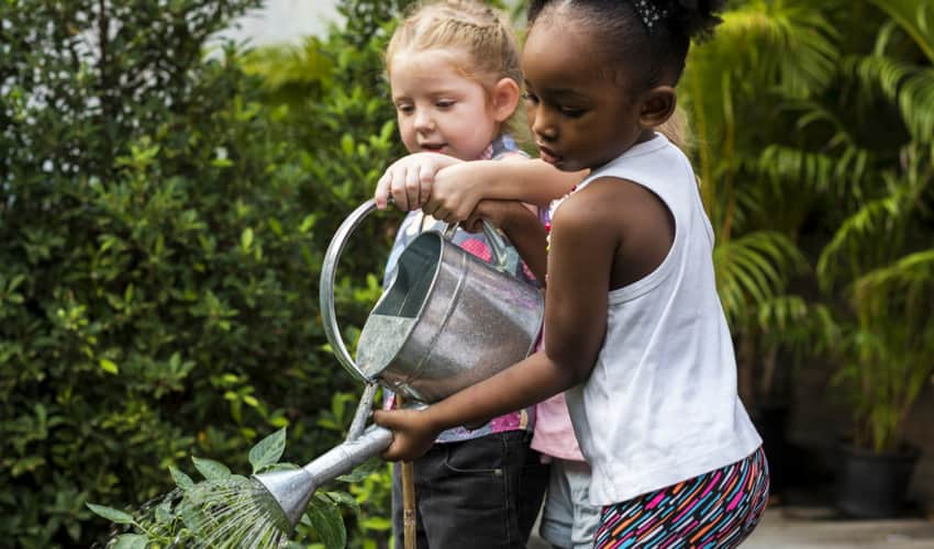 Two children watering a garden 