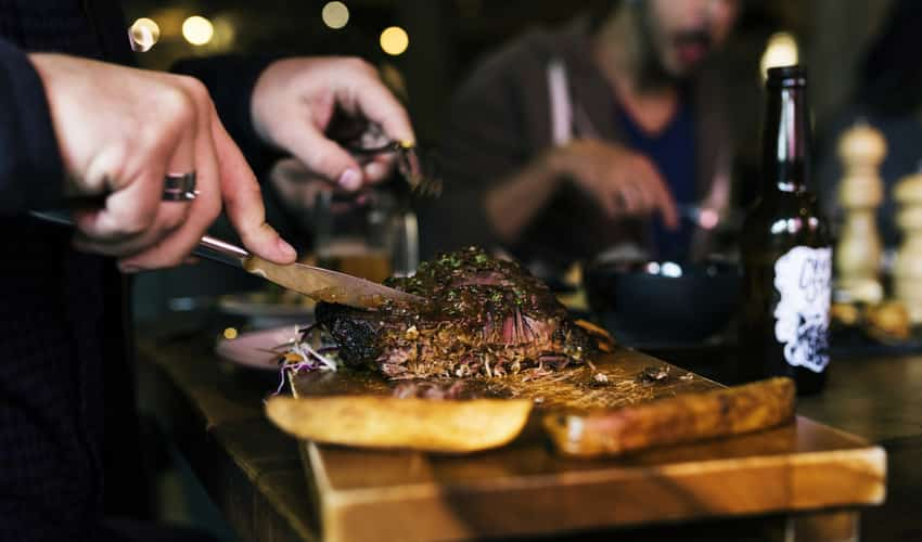 Close up of a man cutting a steak