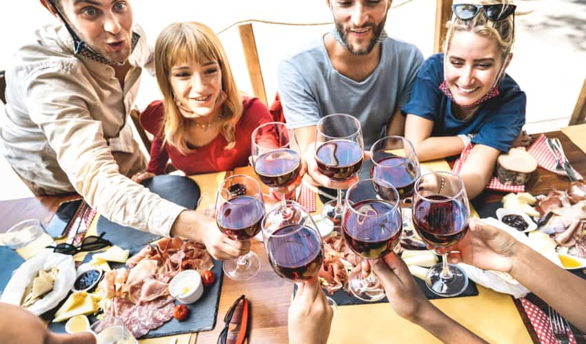 A group of friends toasting glasses of wine over dinner