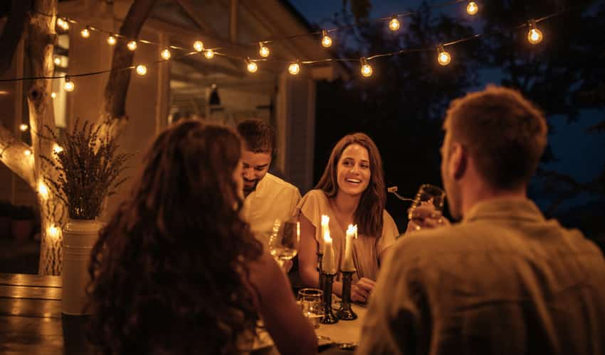 People having dinner on a patio under lights in the evening