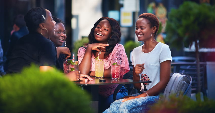 A group of friends enjoy colorful cocktails on a restaurant patio