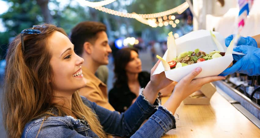 A customer buying food from a food truck in an outdoor space