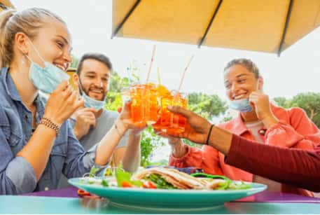 A group of friends toasting drinks over lunch under a patio umbrella