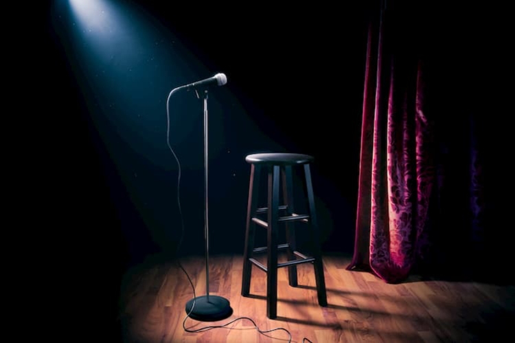 A stage with a spot light, chair and a microphone stand
