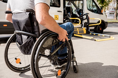 A man in a wheelchair approaches a lift on a bus rental