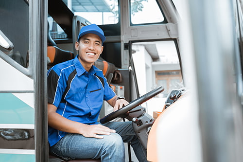 A bus driver smiles at the wheel of a bus