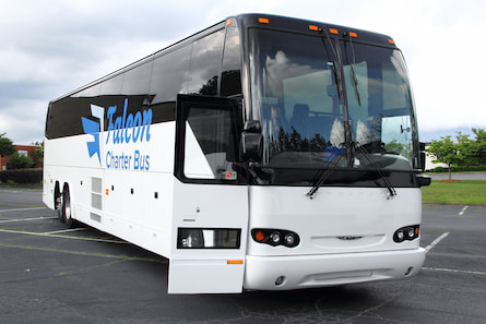A white charter bus with the Falcon Charter Bus logo parked in a lot